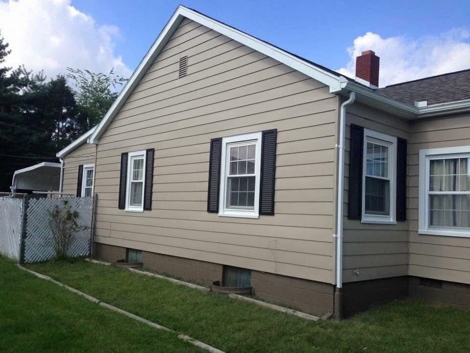 Tan house with white trim, black shutters, and green lawn.