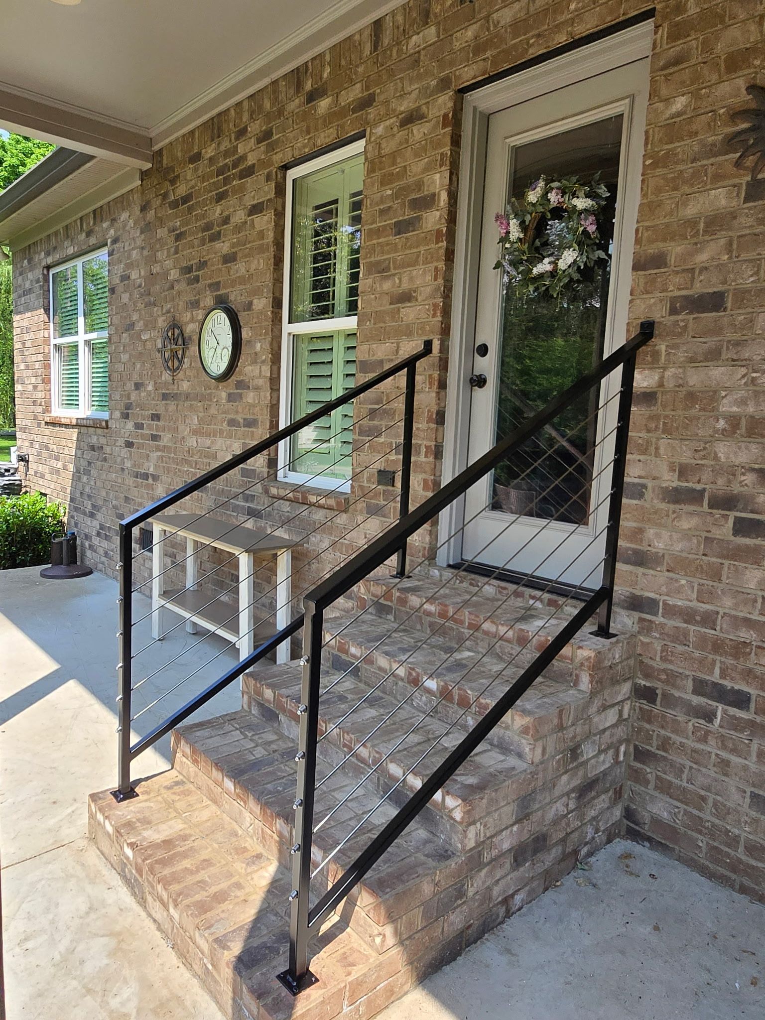 A brick house with a black railing and stairs.