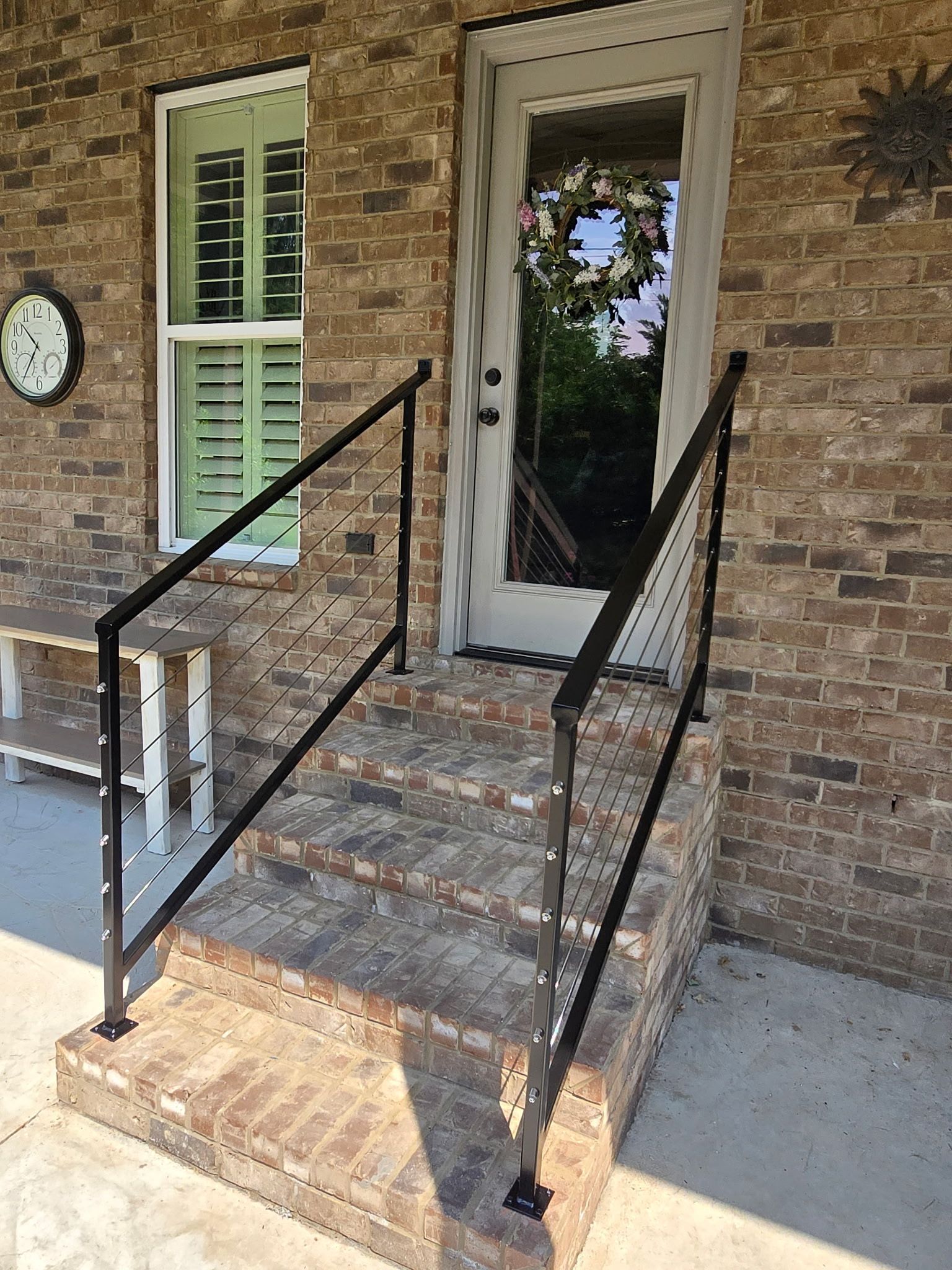 A brick house with a black railing and stairs leading to the door.