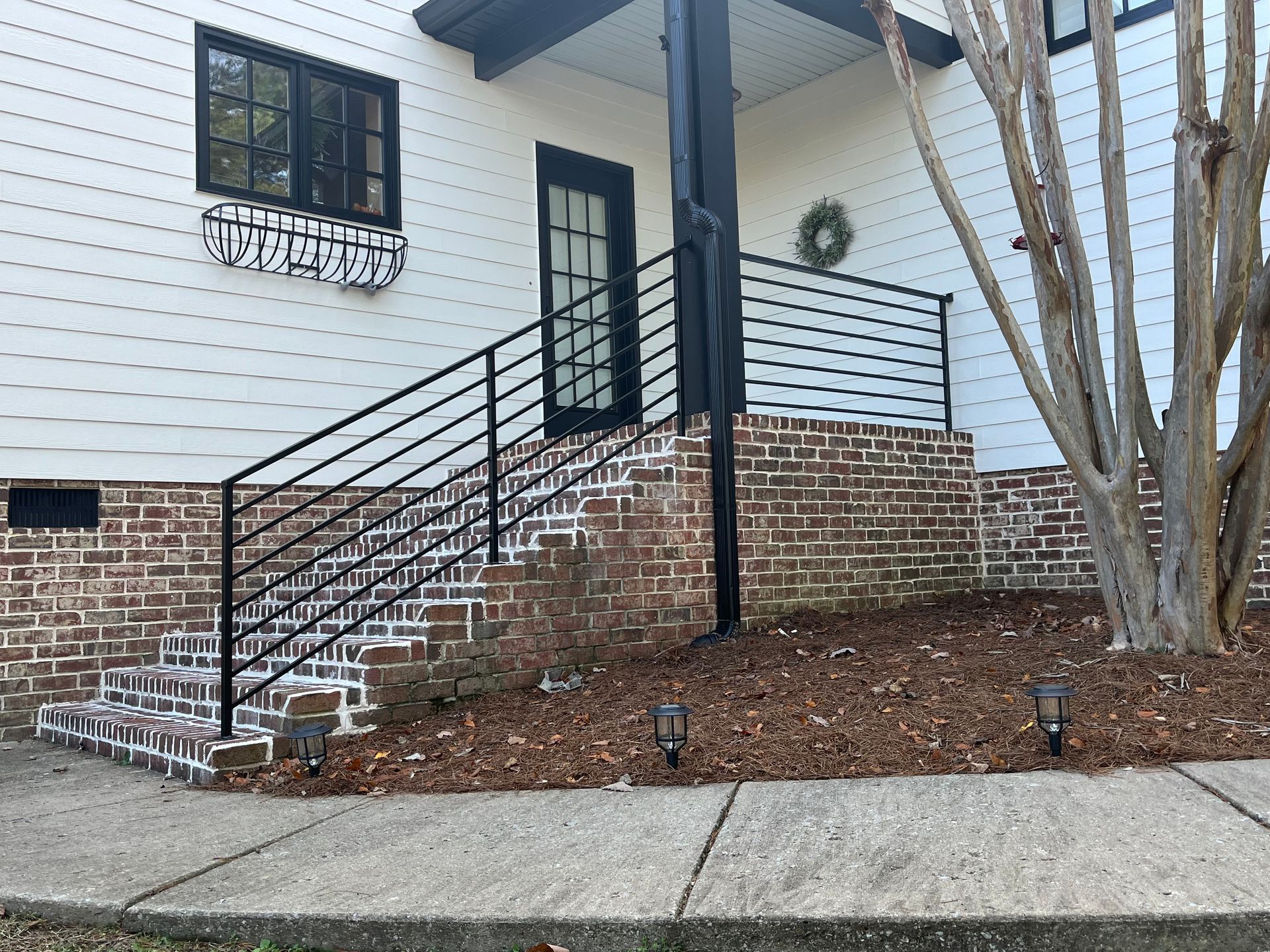 A house with stairs leading up to the front door and a black railing.