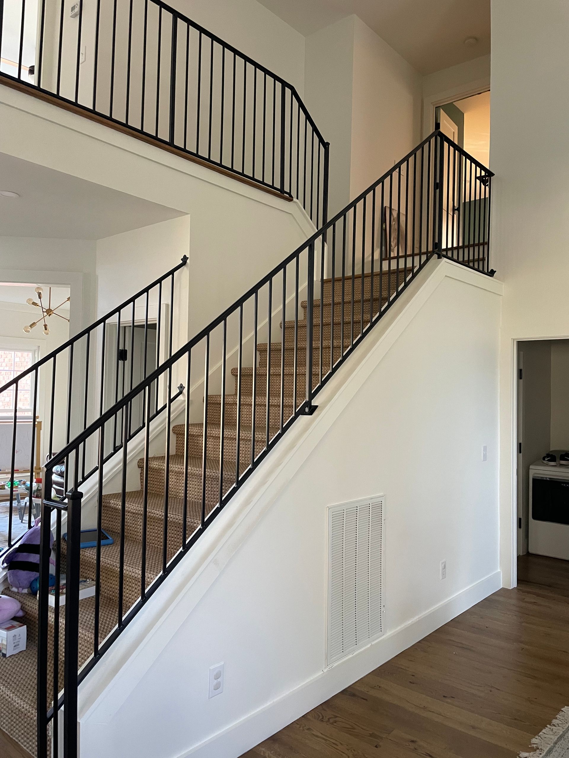 A staircase in a house with a black railing leading up to the second floor.