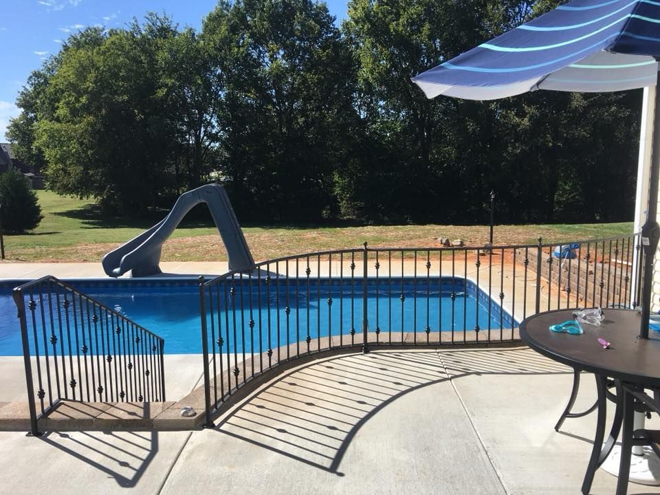 A swimming pool with a slide and an umbrella in front of it