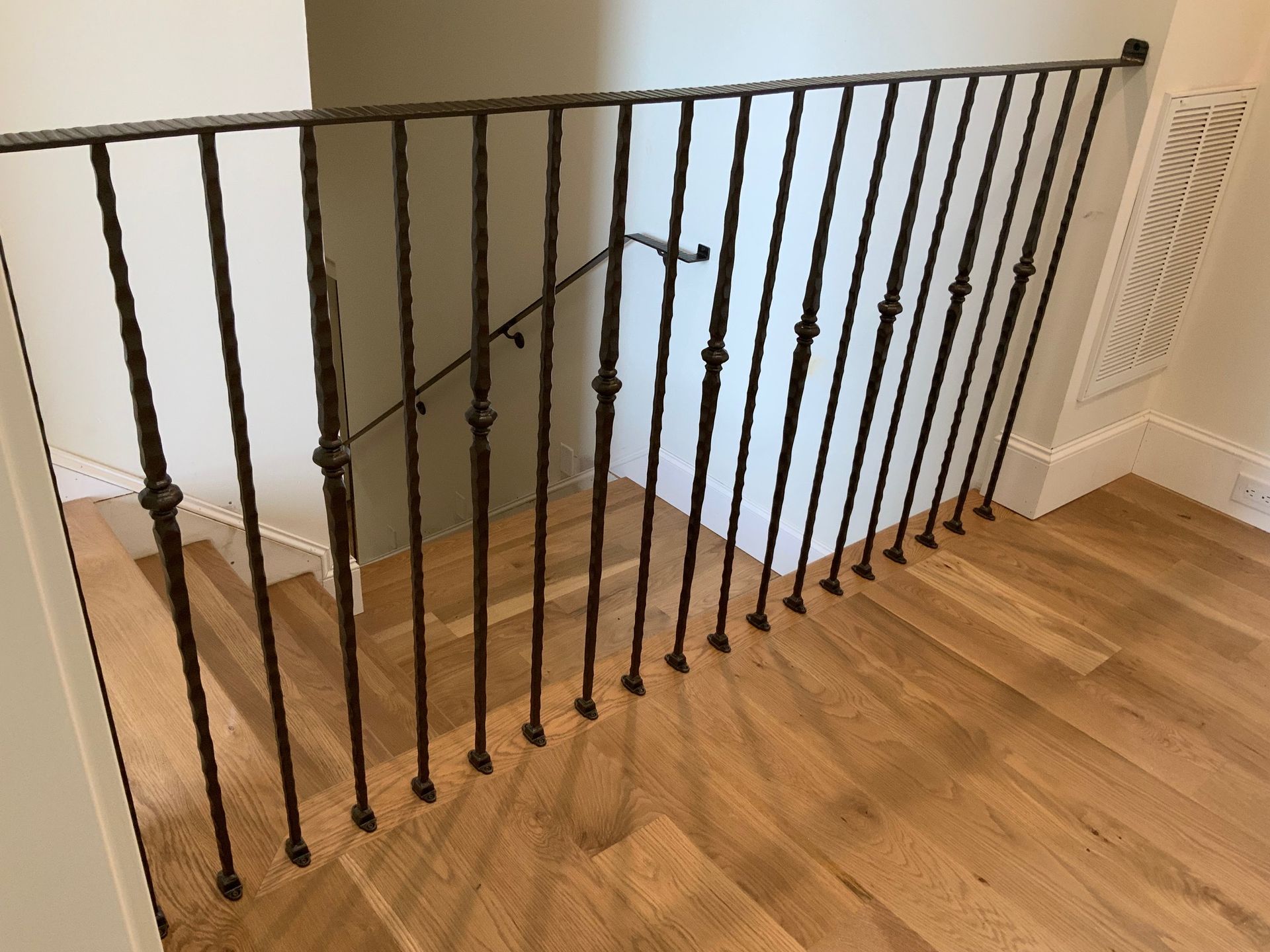 A staircase with a wrought iron railing and wooden floors.