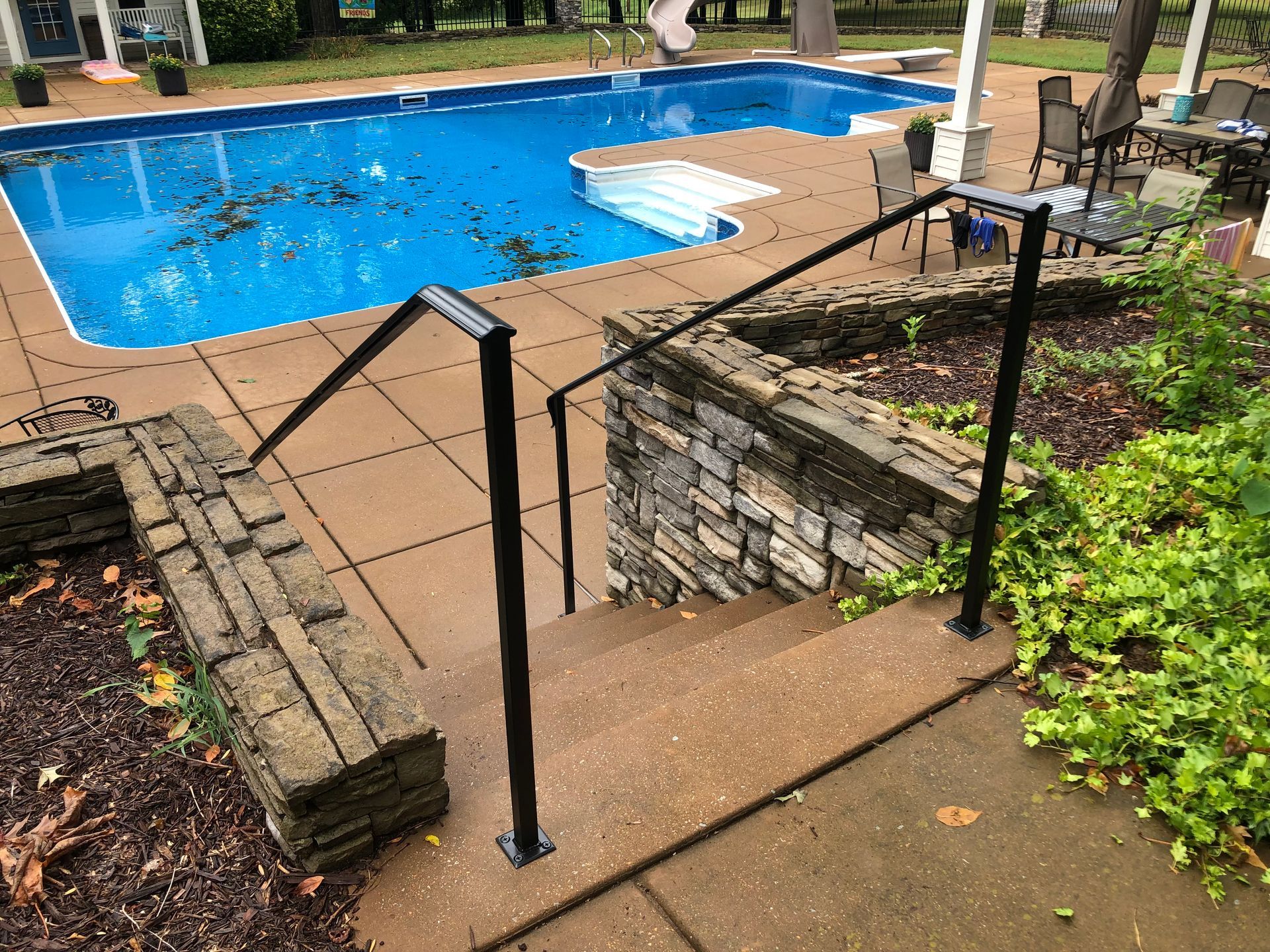 A staircase leading to a swimming pool with a railing.