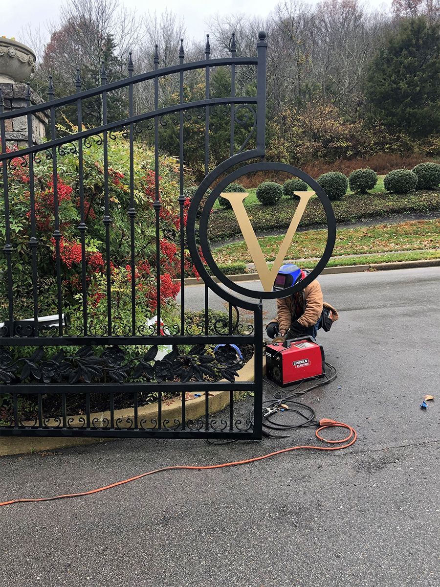 A man is welding a gate on the side of the road.
