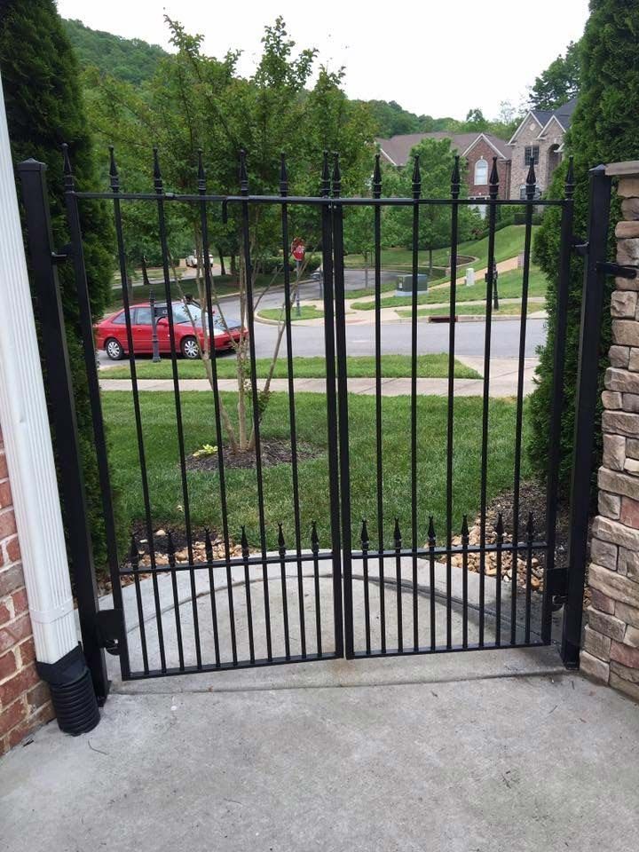 A black gate with a red car parked behind it