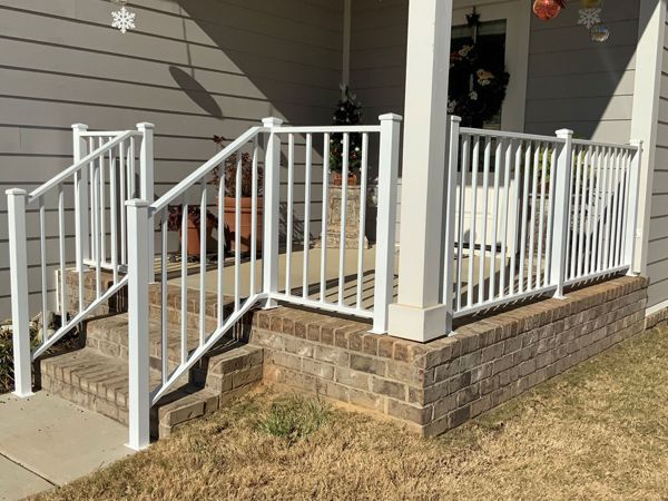 There is a white railing on the porch of a house.