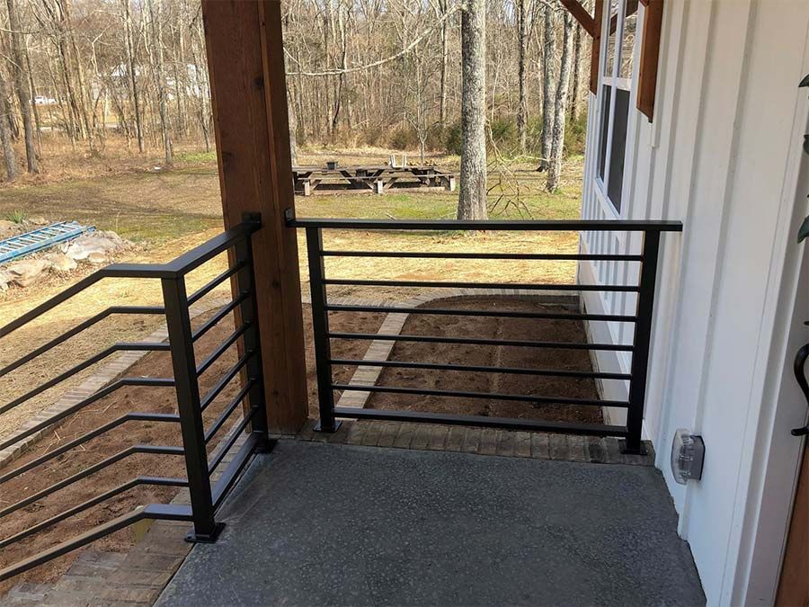 A balcony with a black railing and a picnic table in the background.