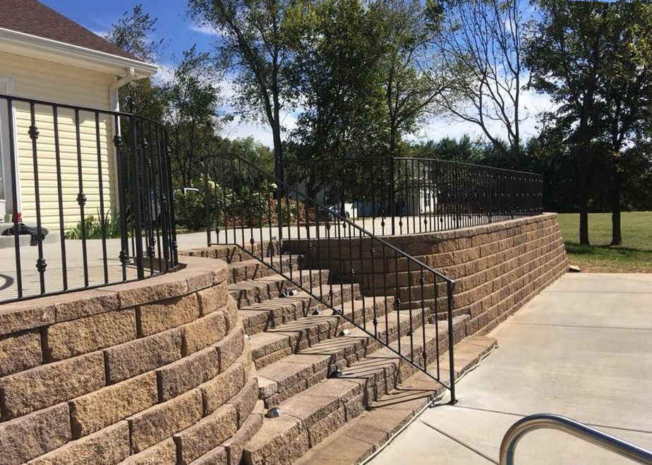 A brick wall with stairs leading up to it and a wrought iron railing.