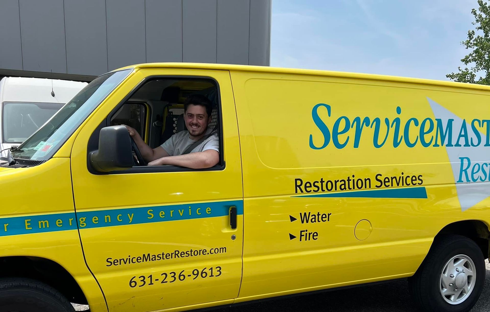 Man smiling in a bright yellow ServiceMaster van. Restoration Services.