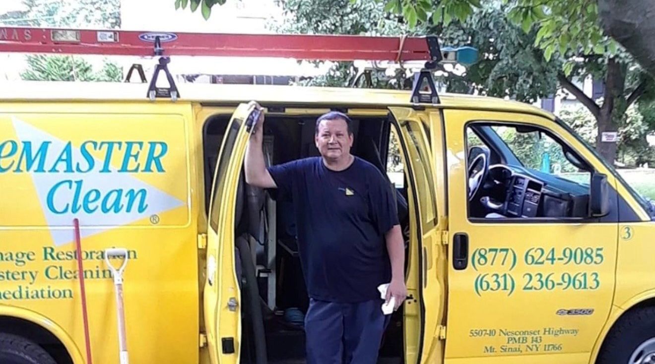 Man standing by a yellow van, likely a restoration service.