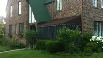 Brick apartment building with green awning and shrubs in front