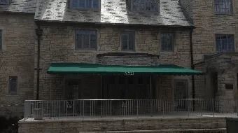 Stone building with a green awning and metal railing by the water