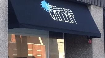 Storefront awning reading “GALLERY” above a glass entrance, with a blue paint-splash logo.