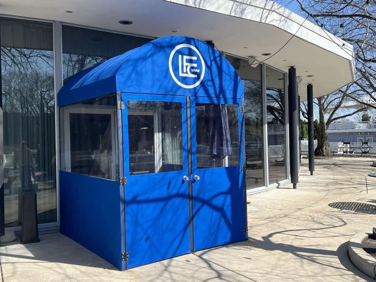 Blue security booth with “IE” logo outside a modern glass building