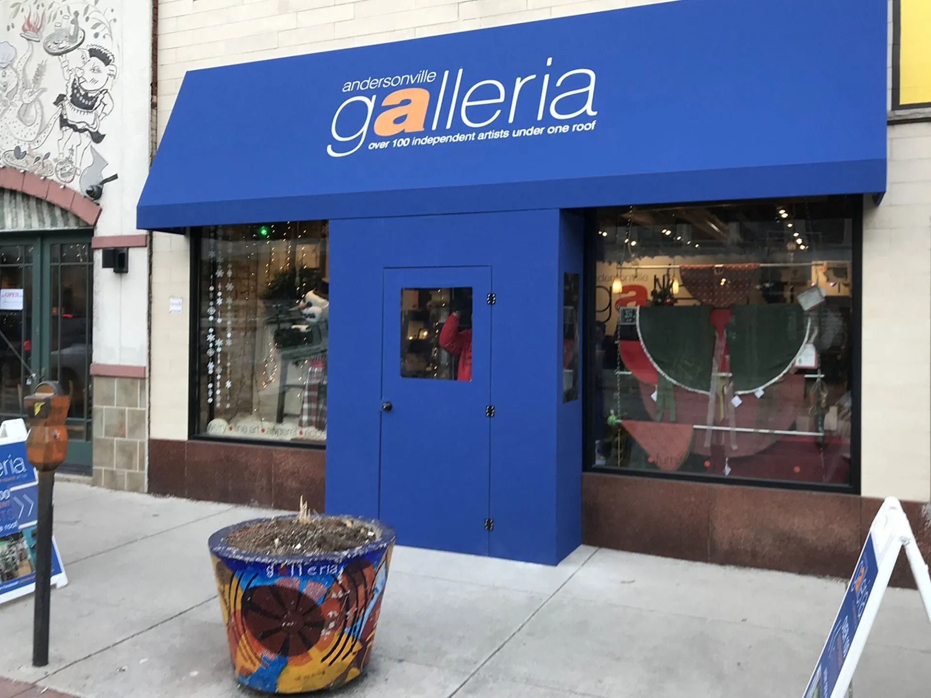 Blue storefront awning and door for “galleria,” with display windows on a city sidewalk