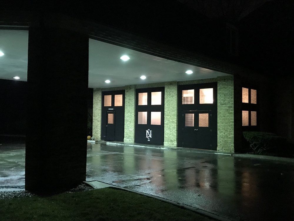 Rainy night at a gas station canopy with lit pumps and wet pavement reflecting lights