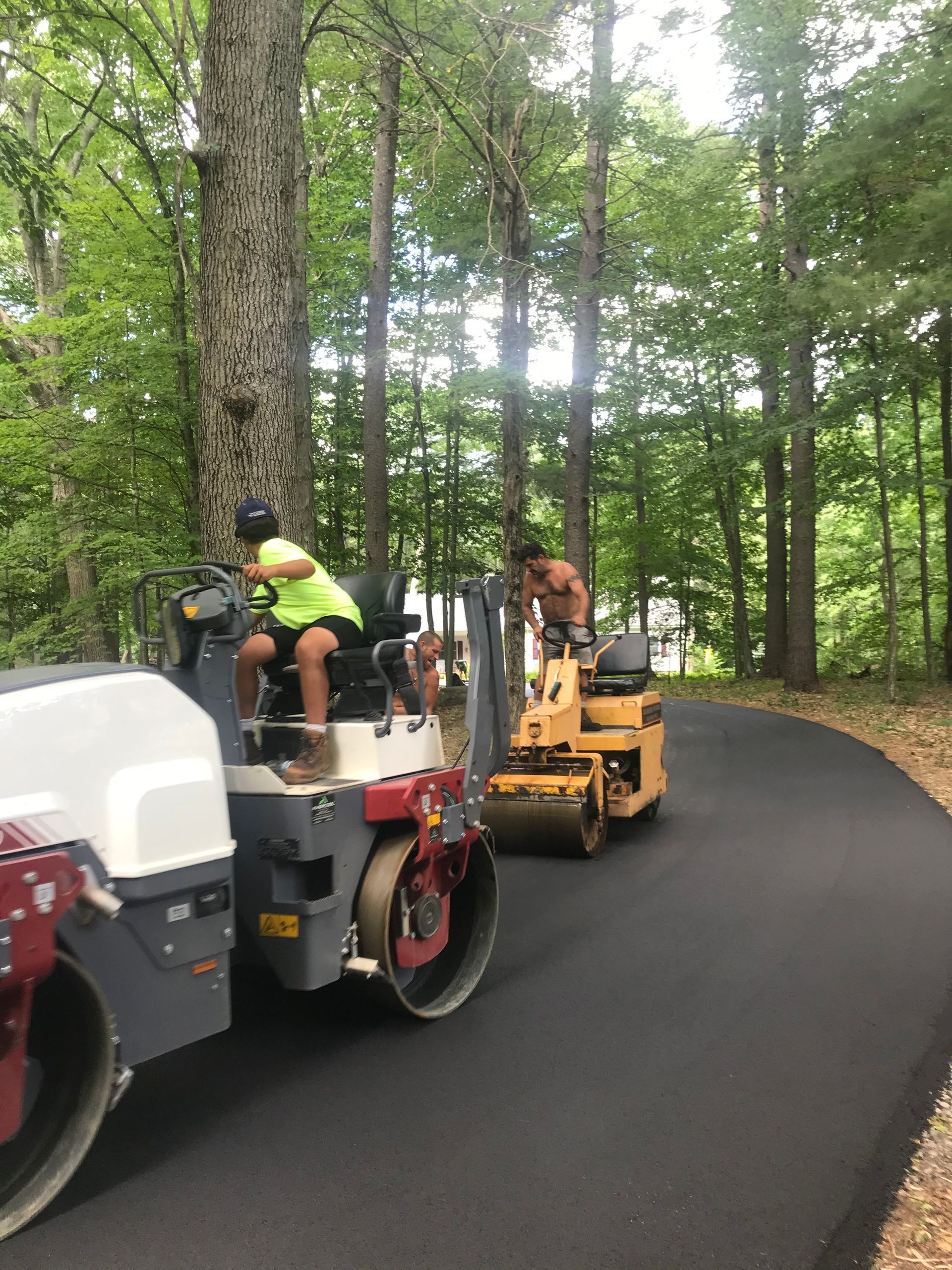 a group of construction workers are working on a road in the woods