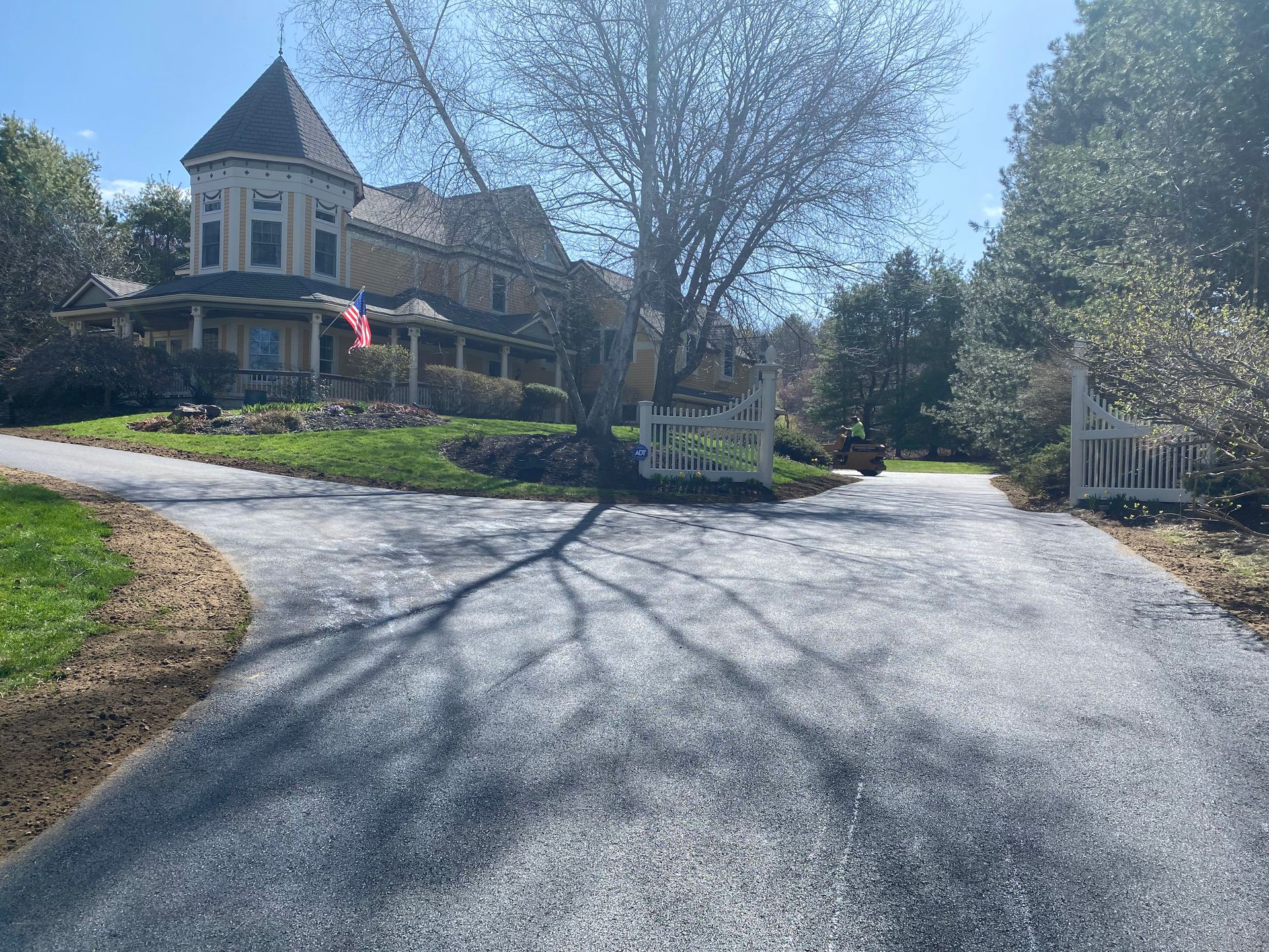 a large house is sitting on top of a lush green hill next to a driveway