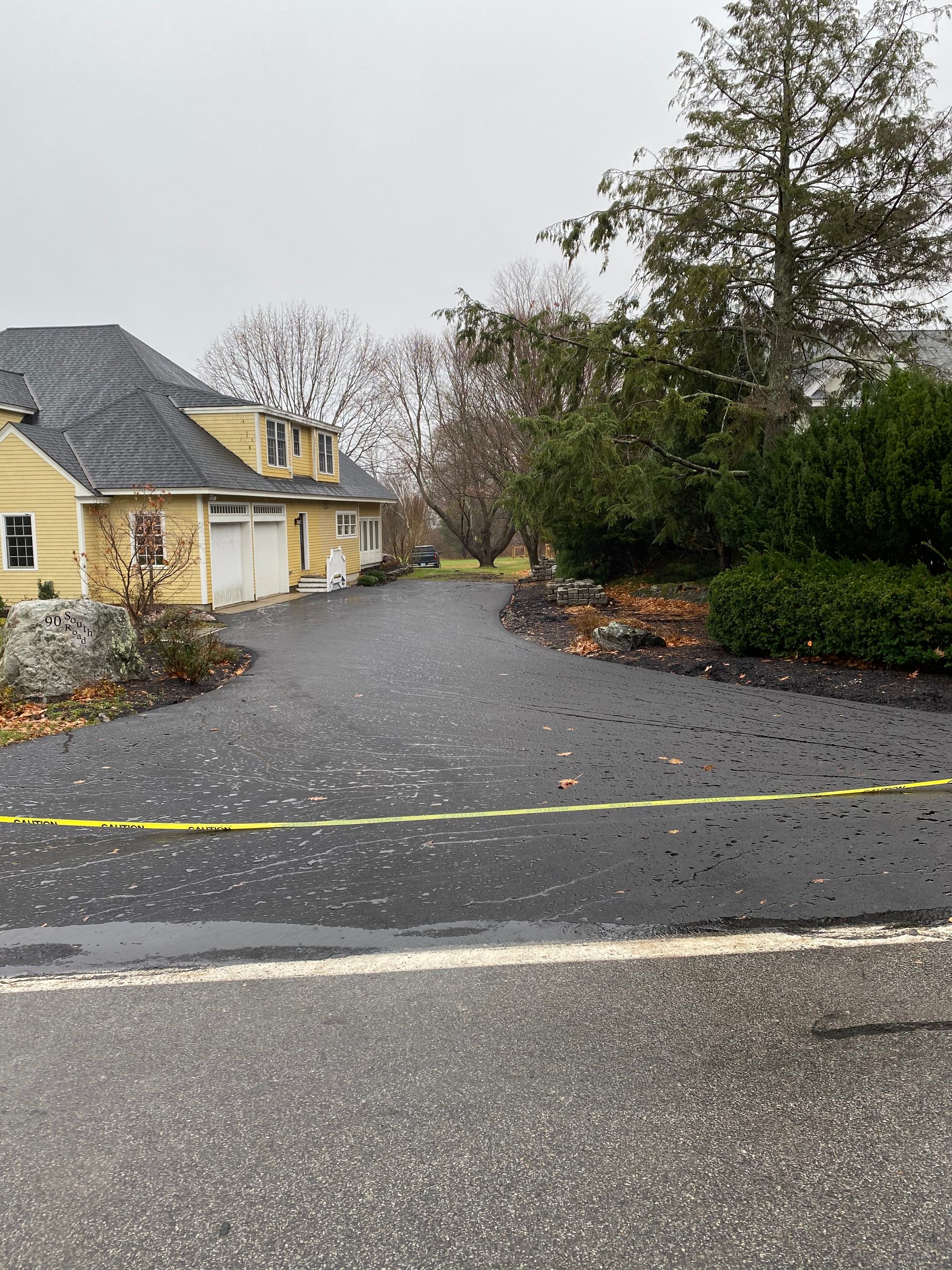 a yellow house is sitting on the side of the road next to a flooded driveway