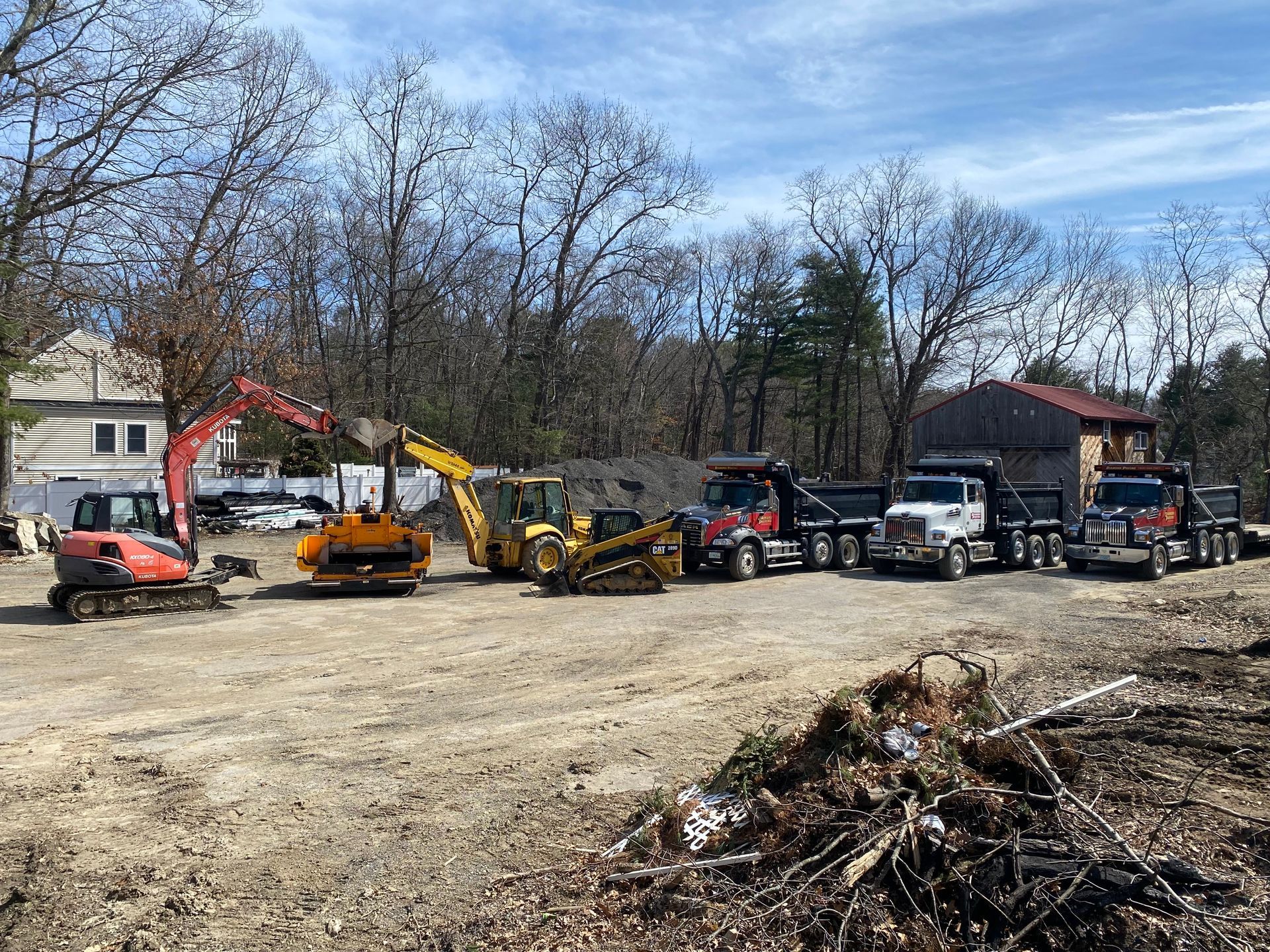 a row of construction vehicles are parked in a dirt lot