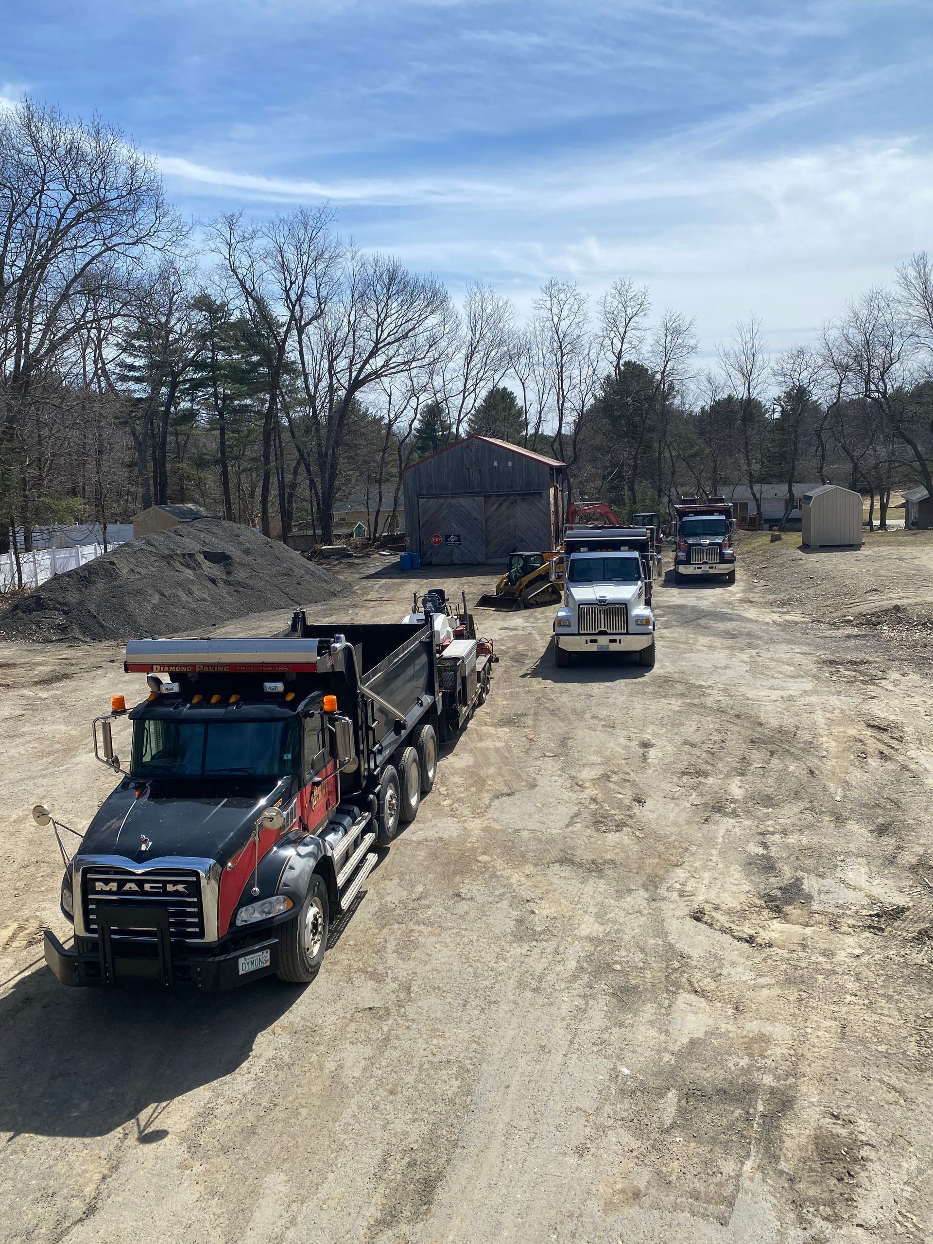 a row of dump trucks are driving down a dirt road