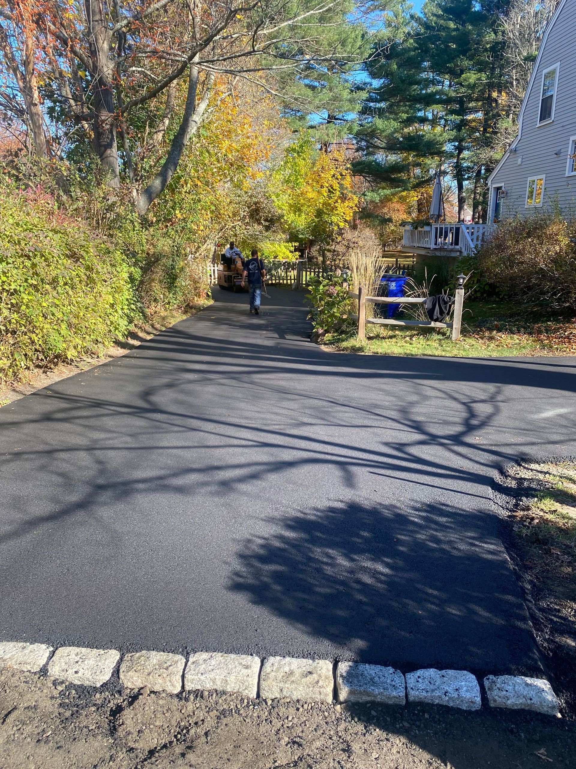 a man is walking down a driveway next to a house