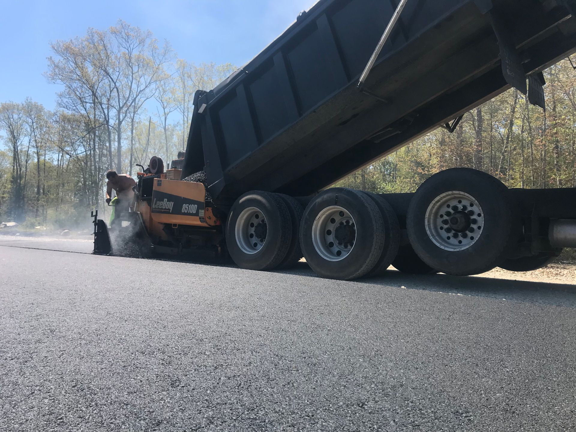 a dump truck is being loaded with asphalt on a road