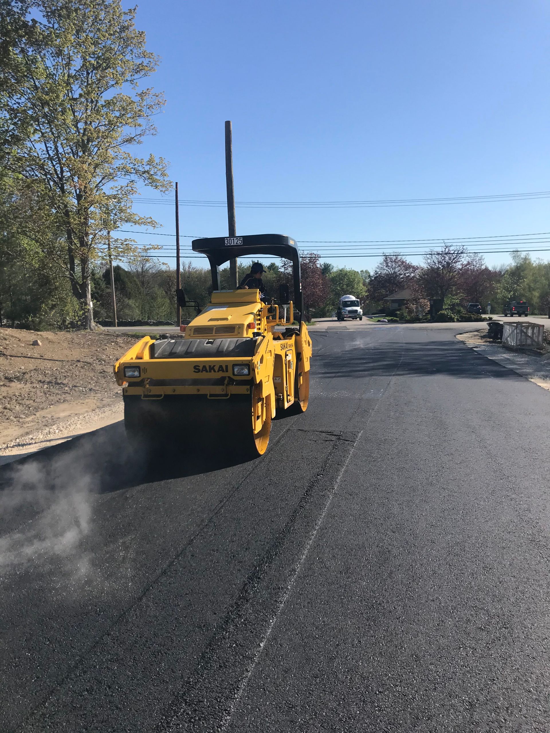a yellow roller is rolling asphalt on a road