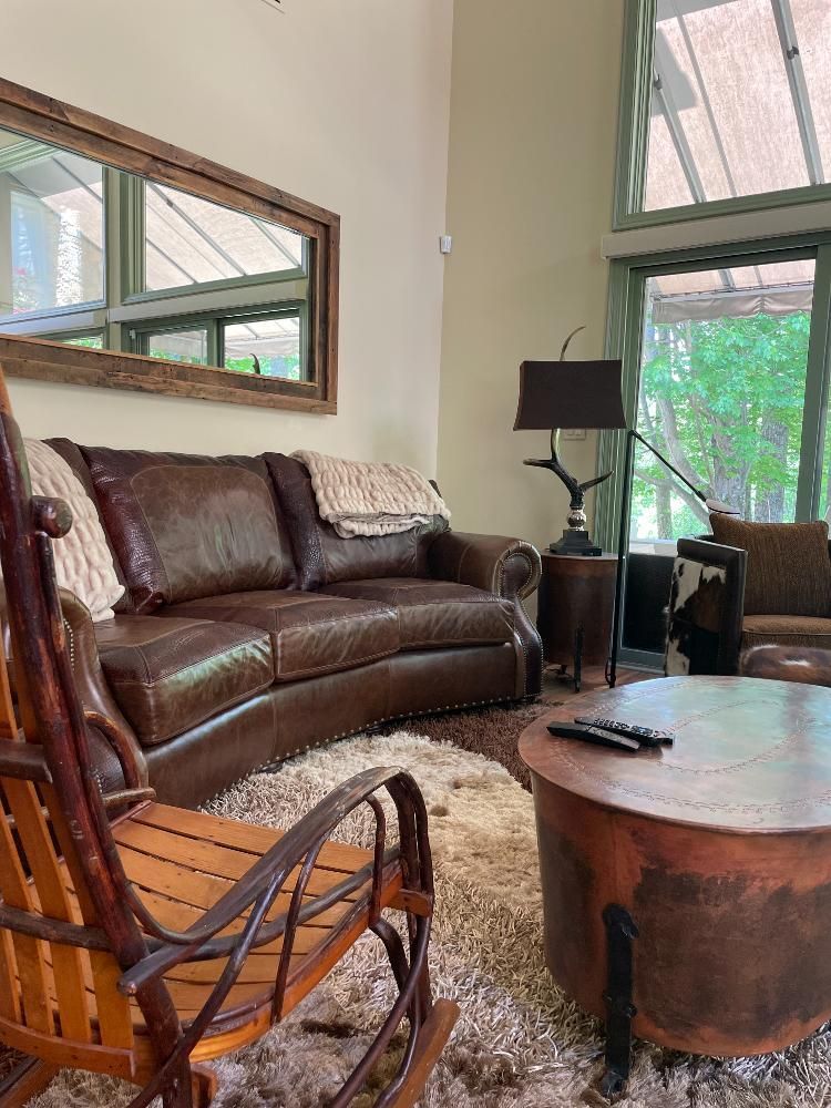 A living room with a couch , rocking chair , coffee table and mirror.