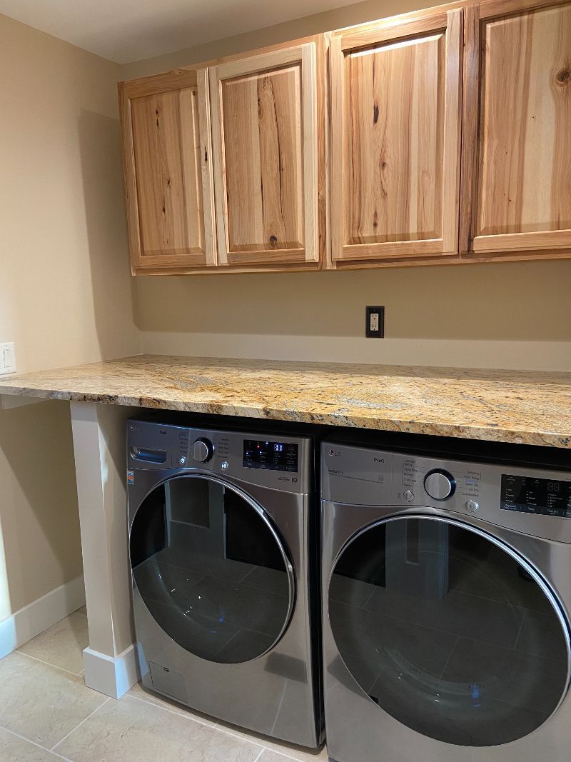 A laundry room with two washers and dryers and wooden cabinets.