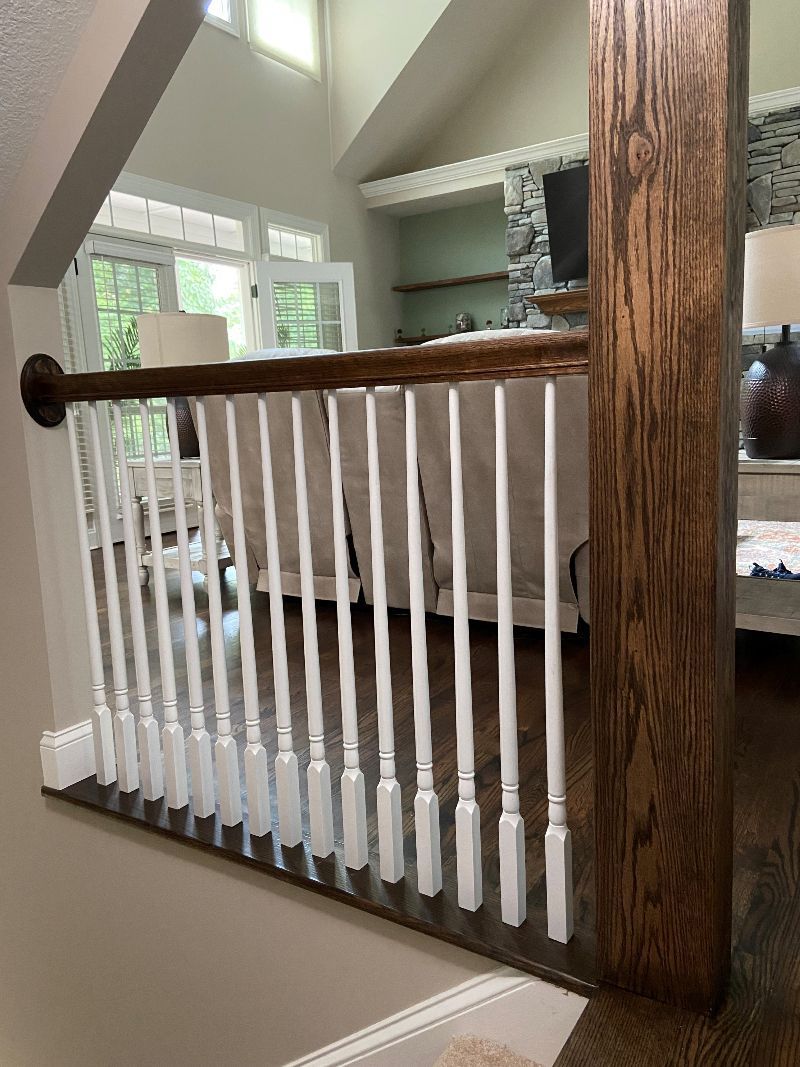 A white railing with a wooden post in a living room.