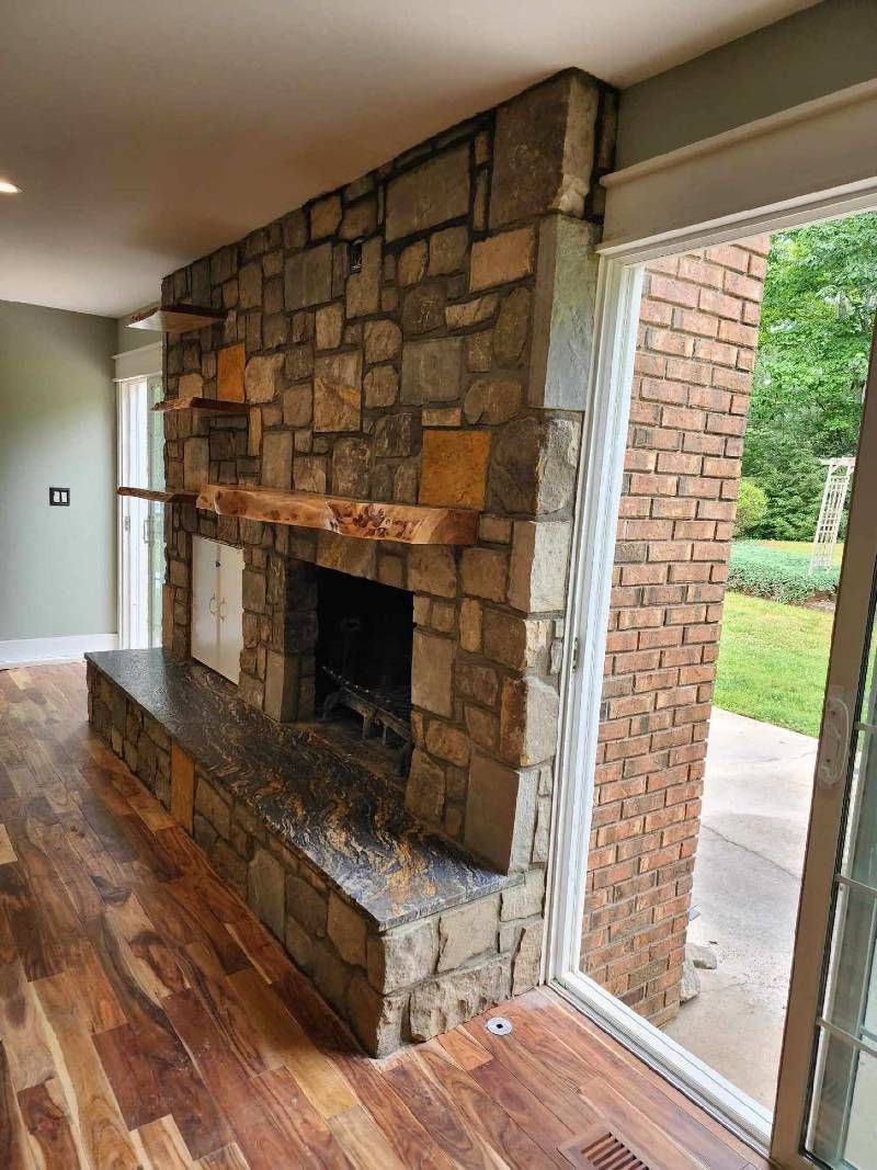 A living room with a stone fireplace and a sliding glass door.