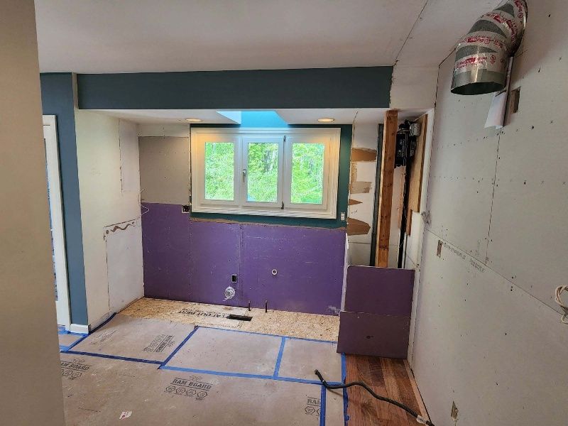 A kitchen under construction with purple walls and a window.