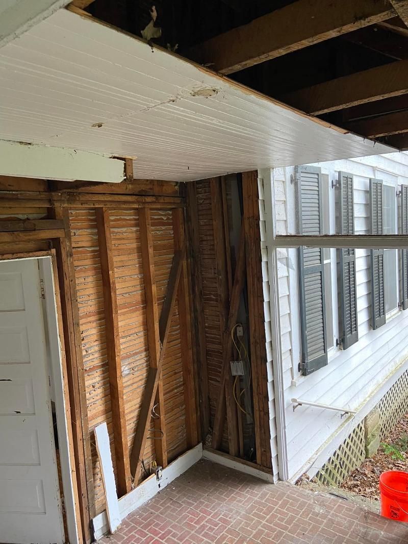 A room with a ceiling that is missing and a bucket on the floor.