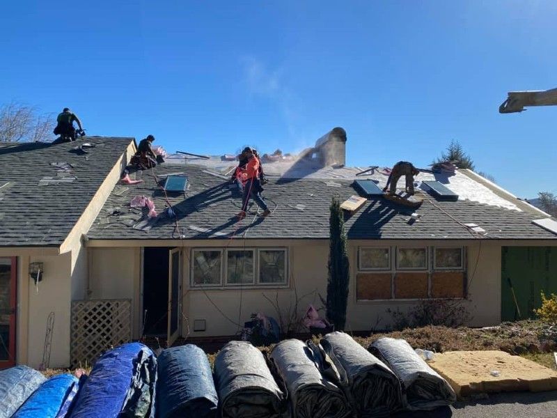 A group of people are working on the roof of a house.
