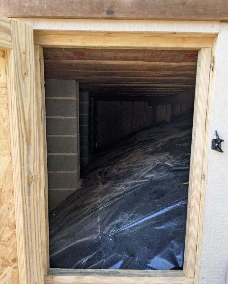 A window in a basement with plastic covering the floor.