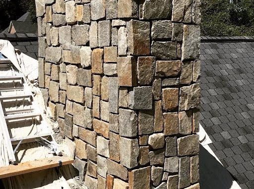 A stone chimney is sitting on top of a brick roof.