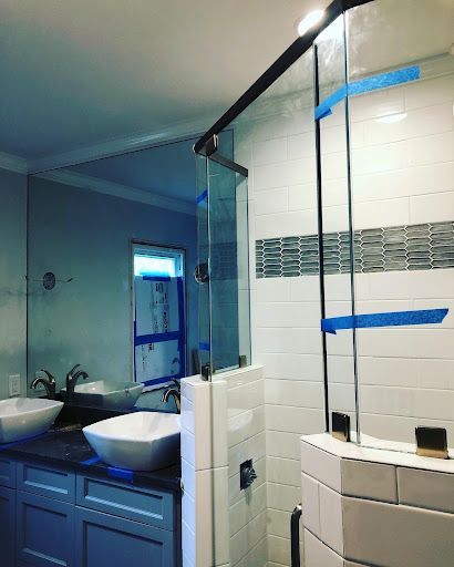 A bathroom with two sinks , a shower and a large mirror.