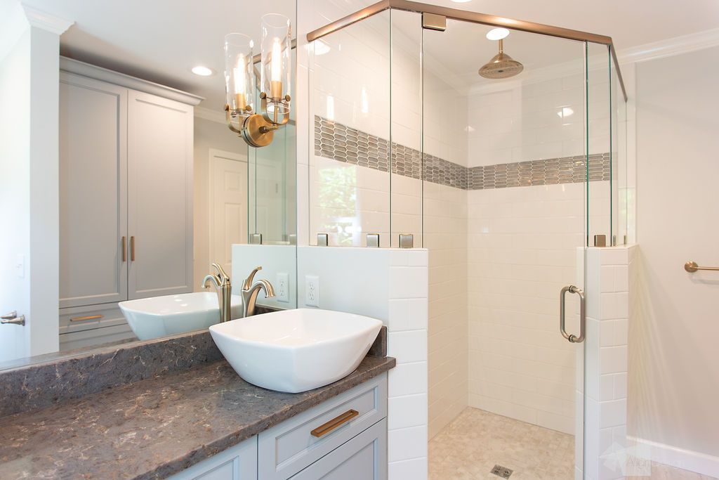 A bathroom with a sink , mirror and walk in shower.