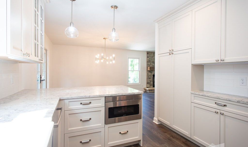 A kitchen with white cabinets , granite counter tops , stainless steel appliances and a large island.