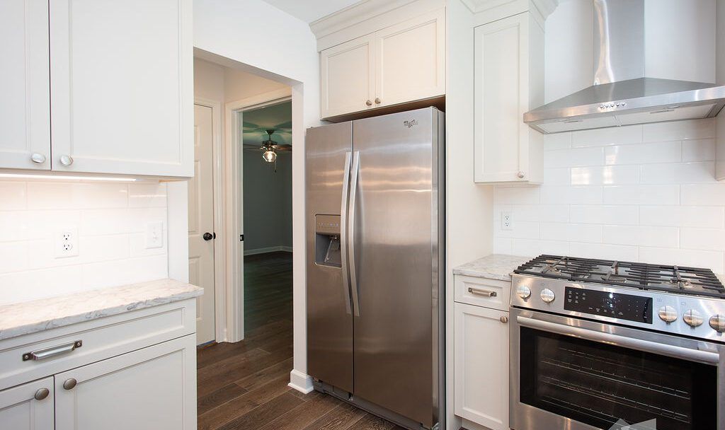 A kitchen with stainless steel appliances and white cabinets.
