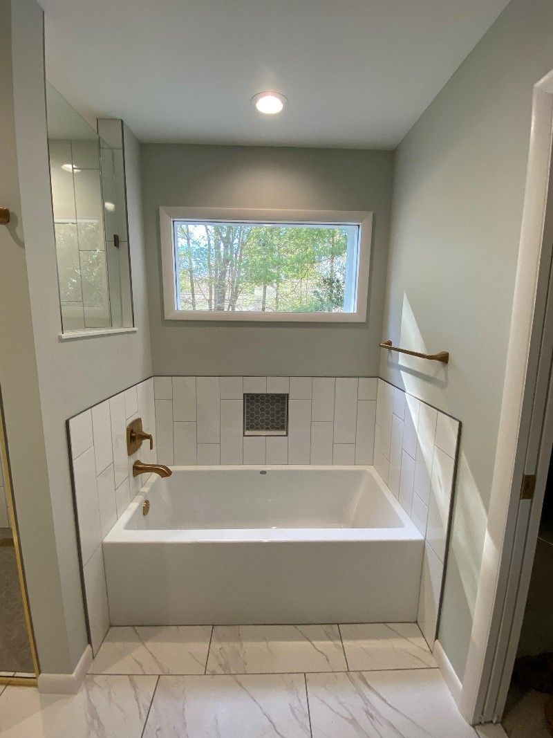 A bathroom with a bathtub and a window.