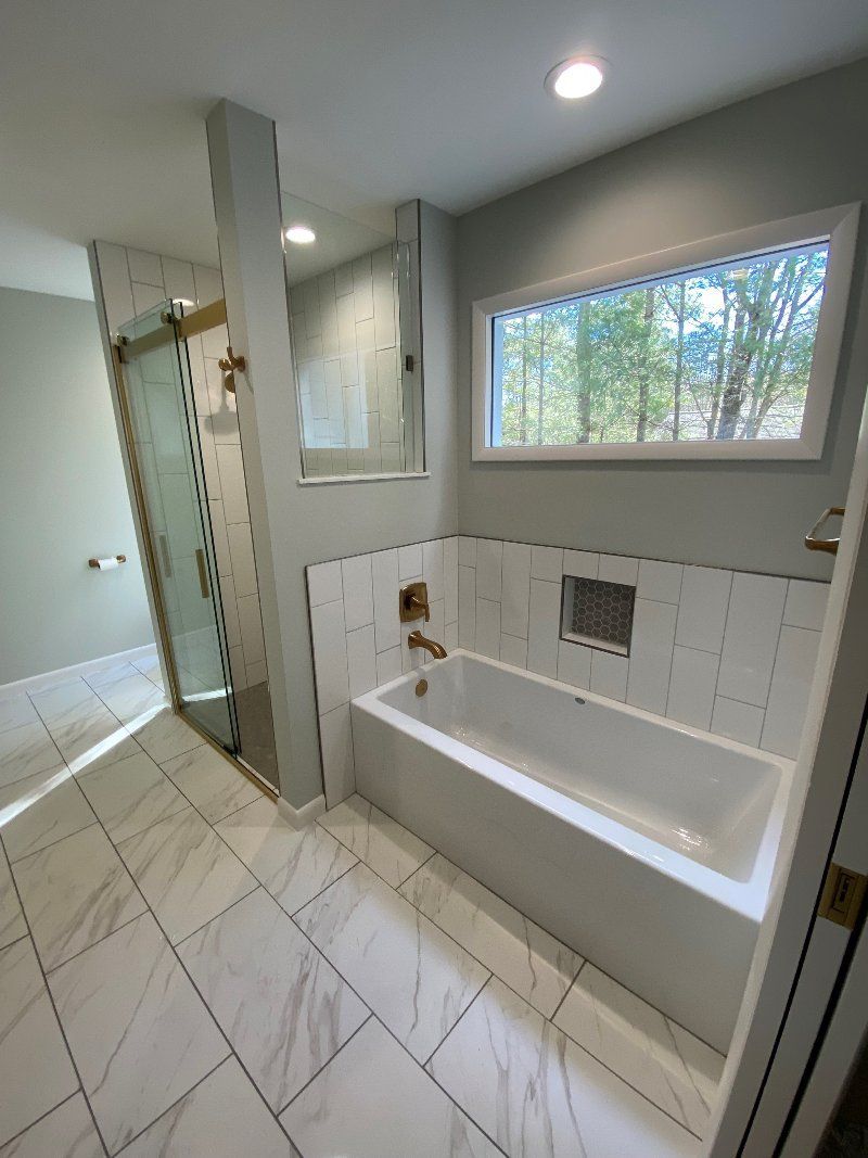 A bathroom with a tub , shower , and window.