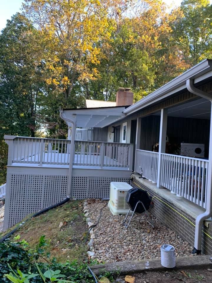 The back of a house with a large deck and trees in the background.