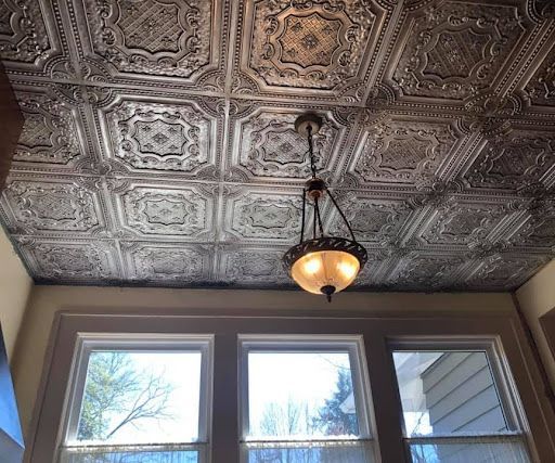 A room with a tiled ceiling and a chandelier hanging from it.