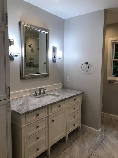 A bathroom with a sink , mirror and cabinets.