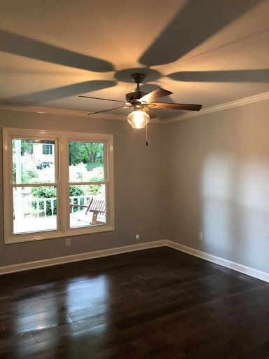 An empty living room with hardwood floors and a ceiling fan.