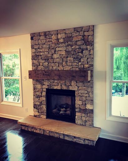 A living room with a stone fireplace and two windows