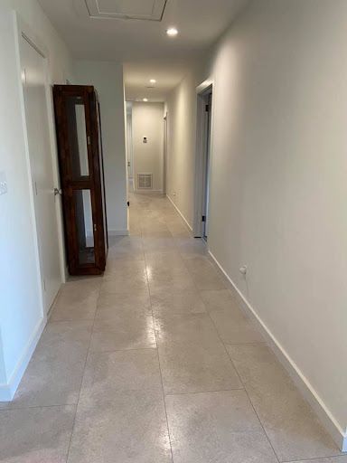 A long hallway with white walls and tile floors in a house.
